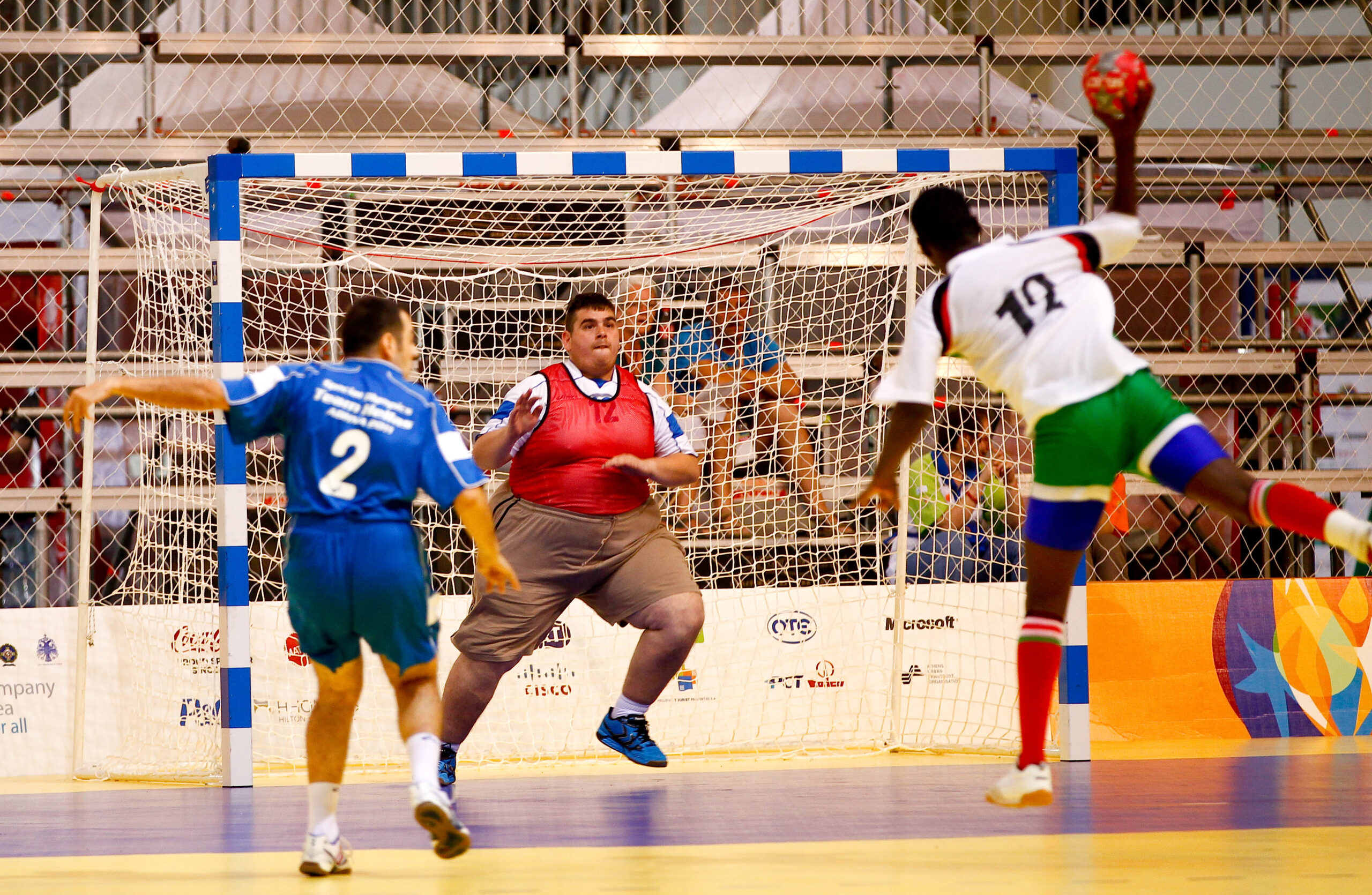 En manlig handbollsspelare siktar bollen mot mål där målvakten står och ser fokuserad ut.